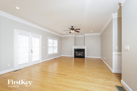 A spacious living room with a fireplace and a ceiling fan.