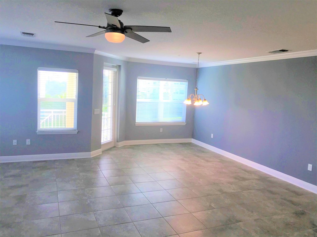 an empty living room with blue walls and a ceiling fan