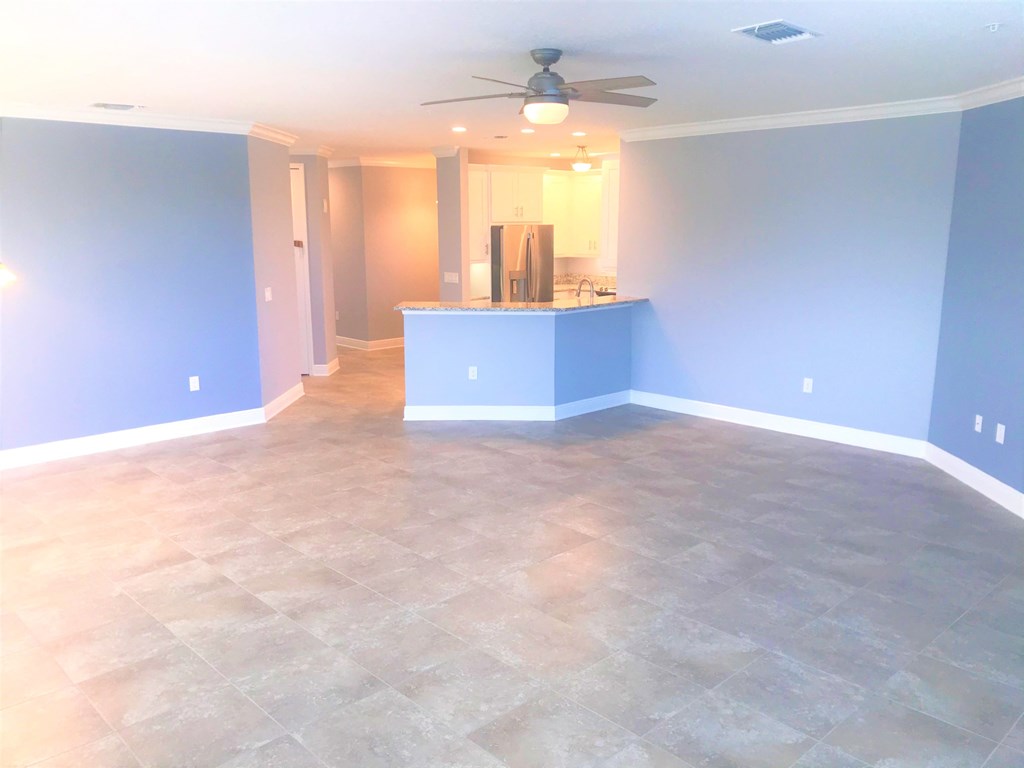 an empty living room with blue walls and a kitchen