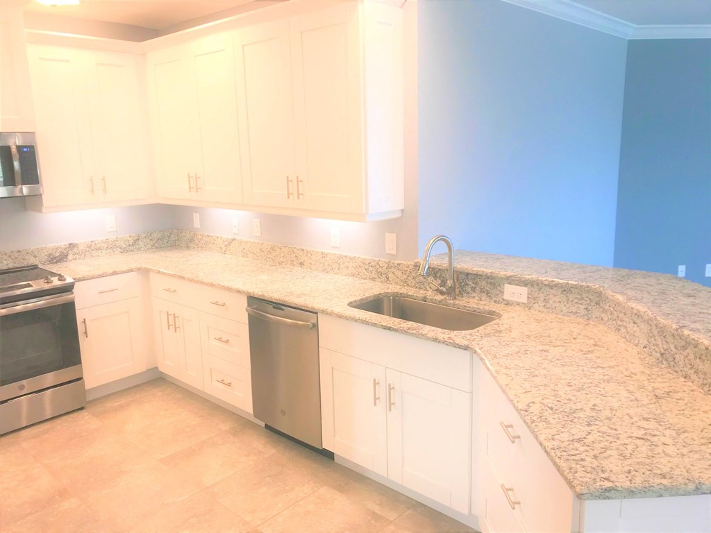 a kitchen with white cabinets and granite counter tops