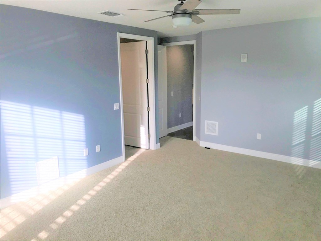 an empty living room with blue walls and a ceiling fan