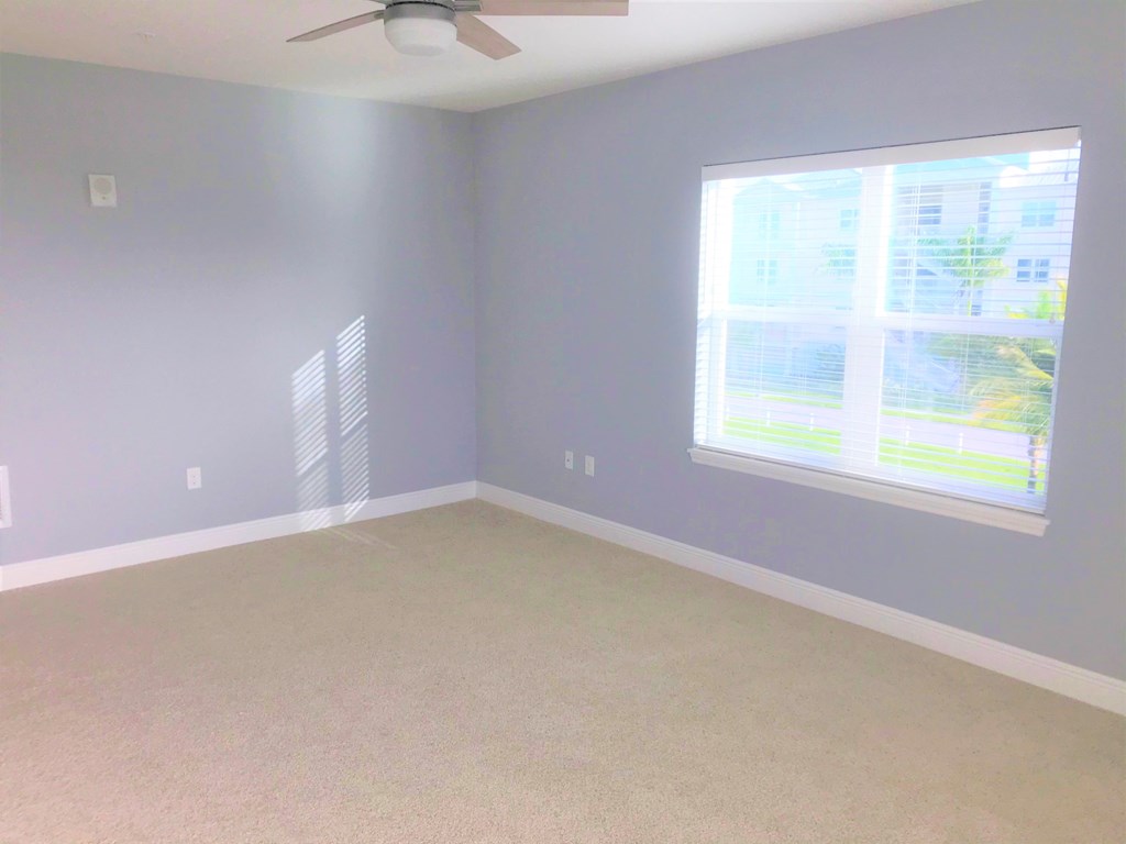 a bedroom with a large window and a carpeted floor