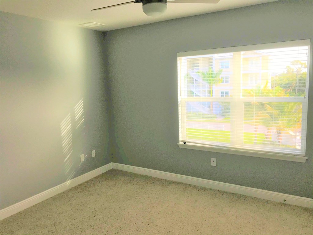 a bedroom with a large window and a carpeted floor