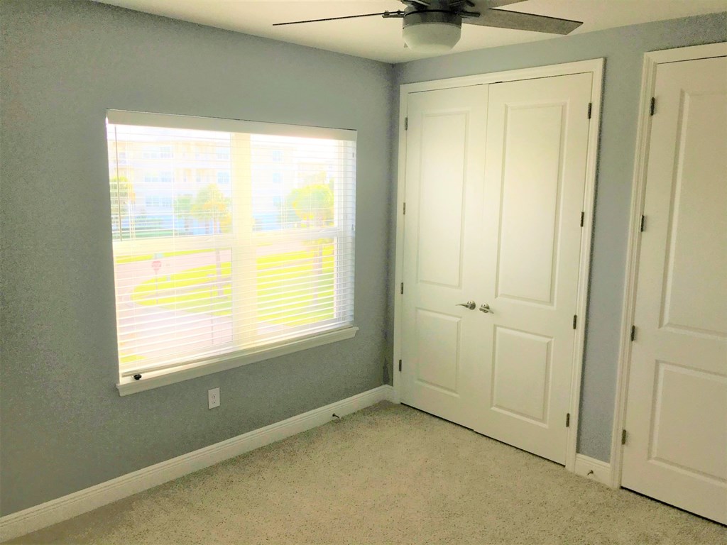 a bedroom with a window and two doors and a ceiling fan