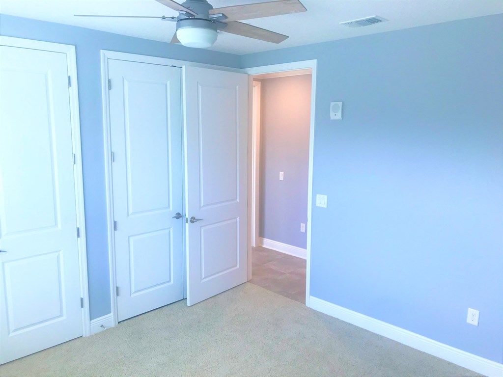 an empty room with two doors and a ceiling fan