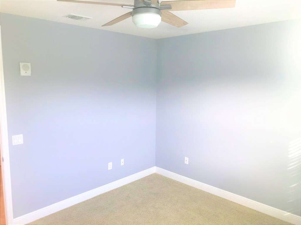 an empty room with blue walls and a ceiling fan