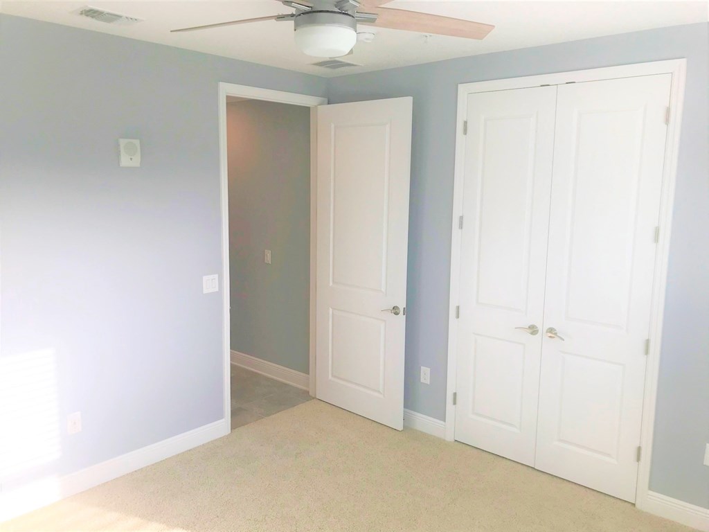an empty room with two closets and a ceiling fan