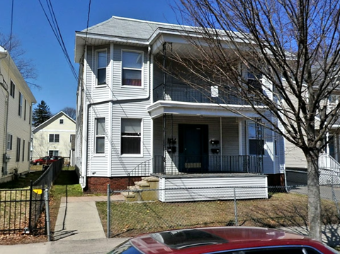 A two-story house with a red car parked in front.