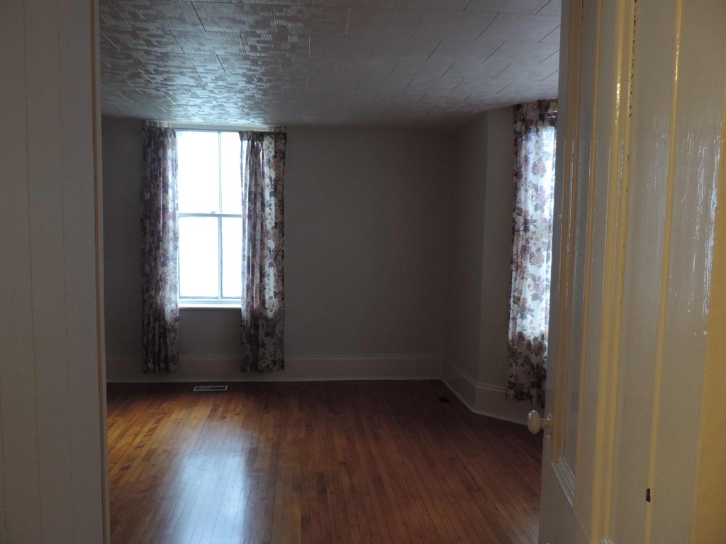 an empty living room with wood floors and curtains