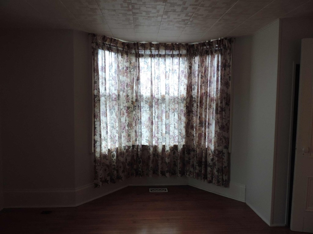a living room with a large window with floral curtains