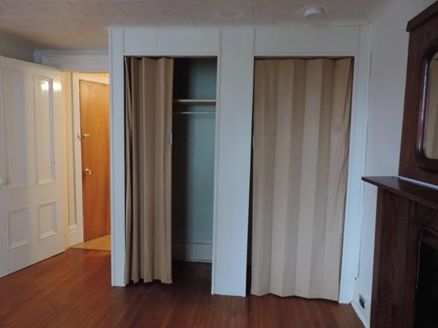 a living room with white curtains and a door to a closet