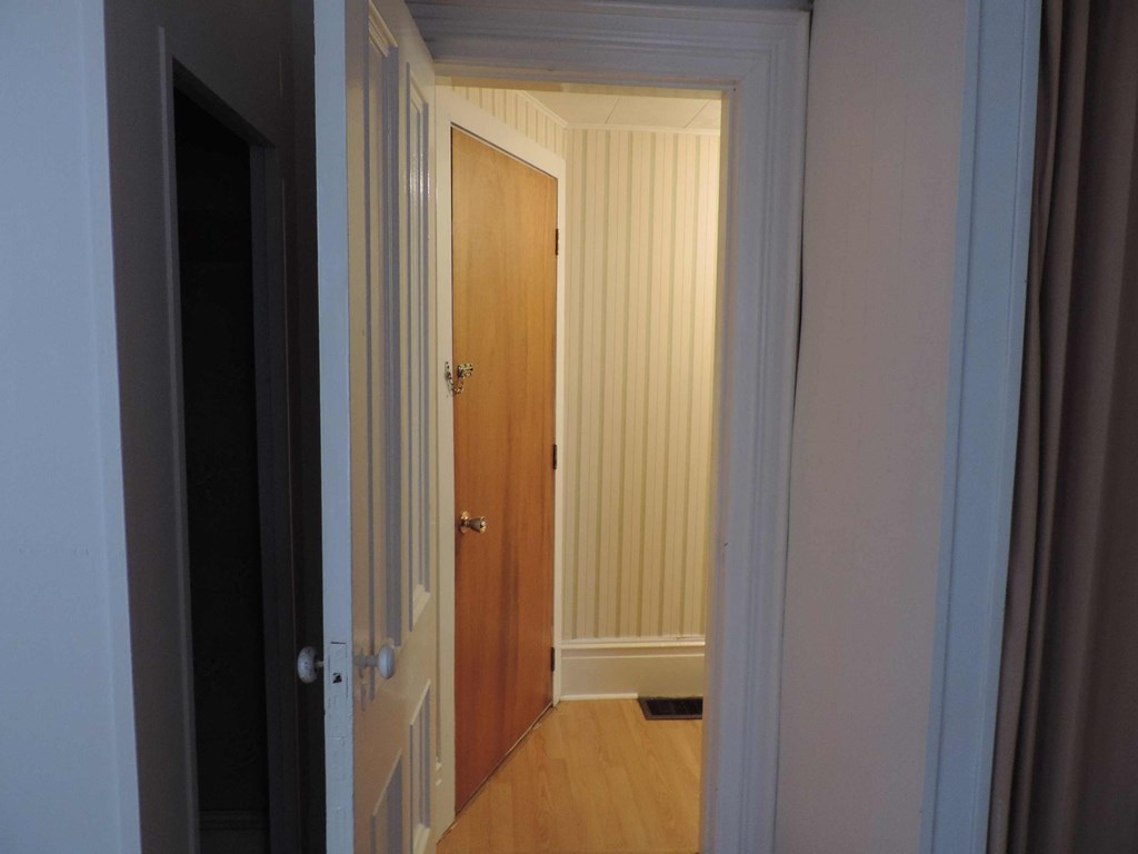 a small hallway with a wooden door and a closet