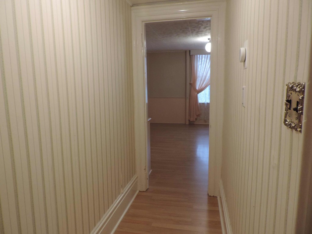 a hallway with white walls and wood floors