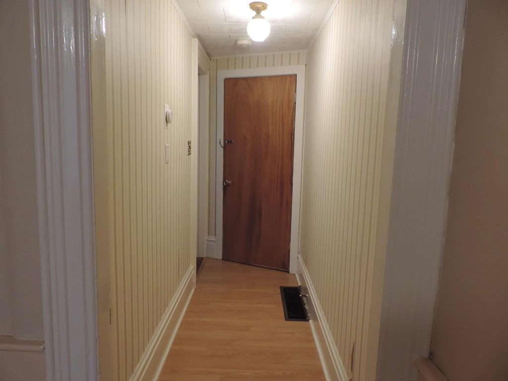 a hallway with white wood paneling and a wooden door