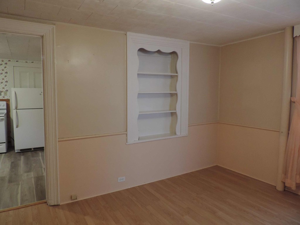 a room with a window and a white shelf in it