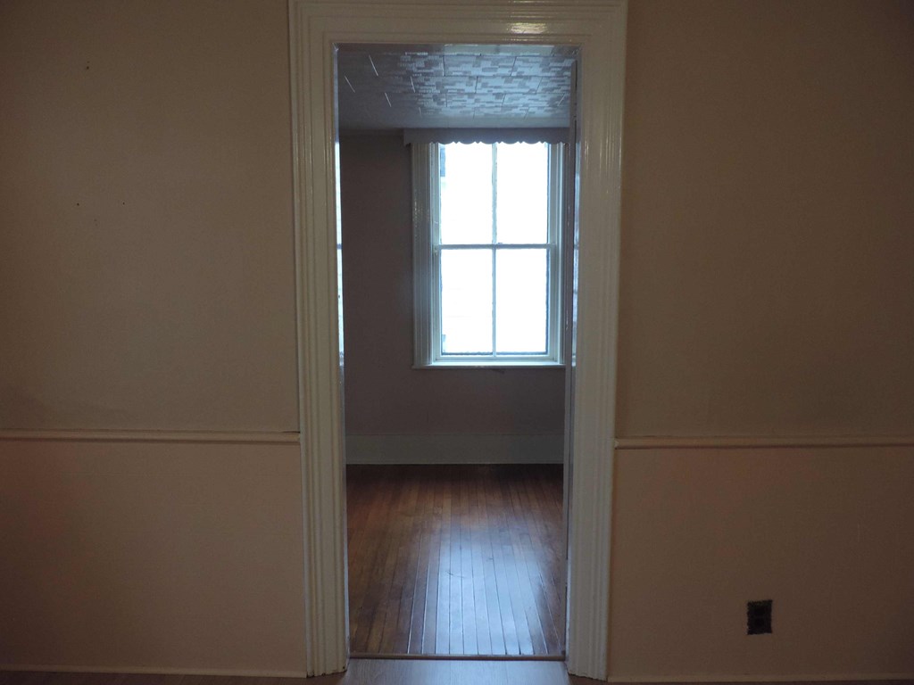 an empty room with a window and wooden floors