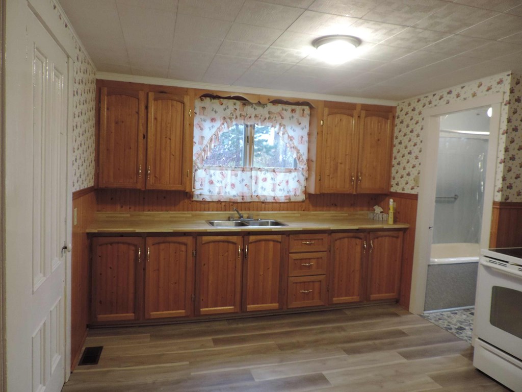 an empty kitchen with wooden cabinets and a window