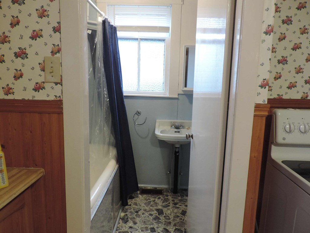 a small bathroom with a sink and shower and a window