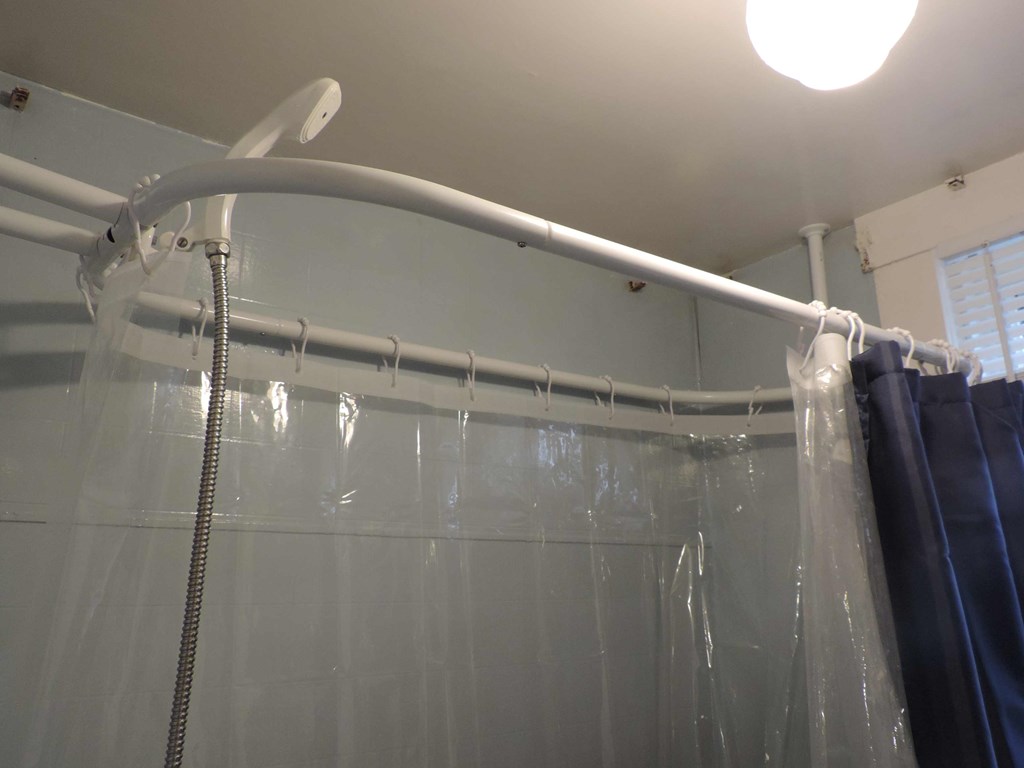 a shower with a white curtain and a curtain rod and a shower curtain