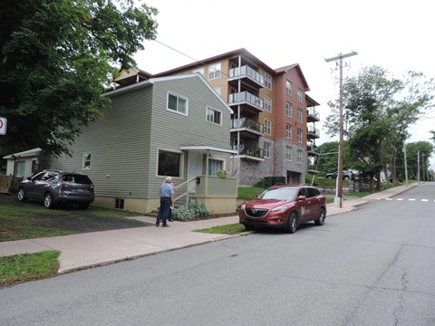 a man walking down a sidewalk in front of an apartment building