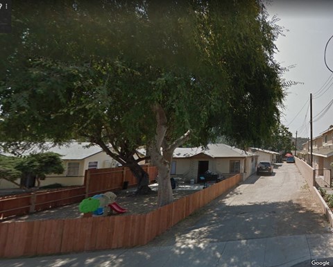 a street with houses and trees and a fence