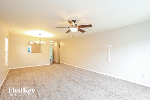 a living room with a ceiling fan and a carpeted floor