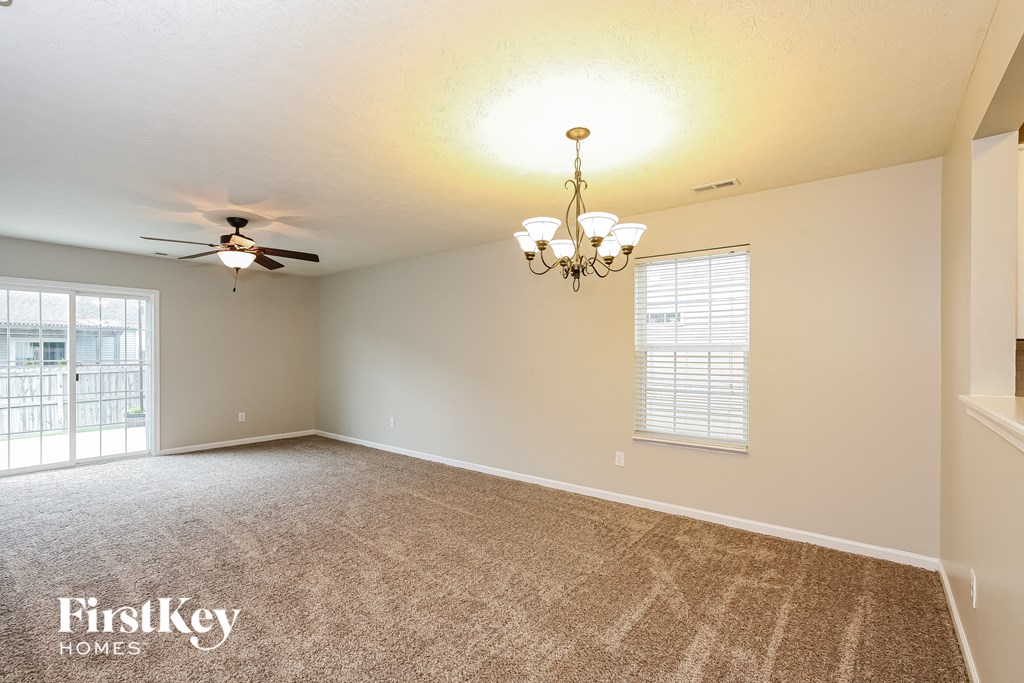 an empty living room with a ceiling fan and a window