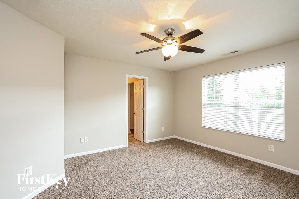 the master bedroom has a ceiling fan and a large window