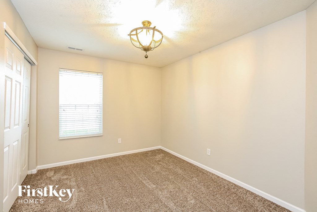 the spacious bedroom with carpeted flooring and a large window