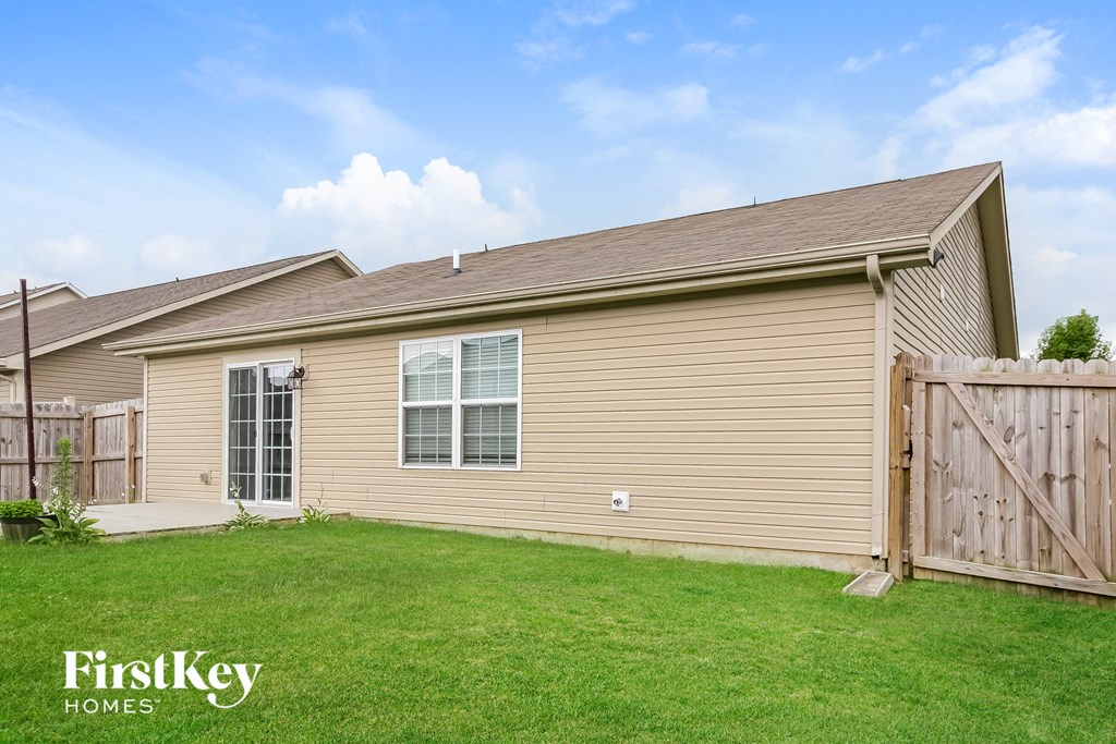 the backyard of a house with a yard and a wooden fence