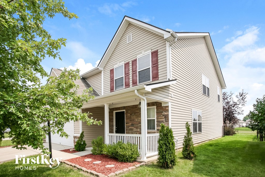 a white house with red shutters and a lawn and trees