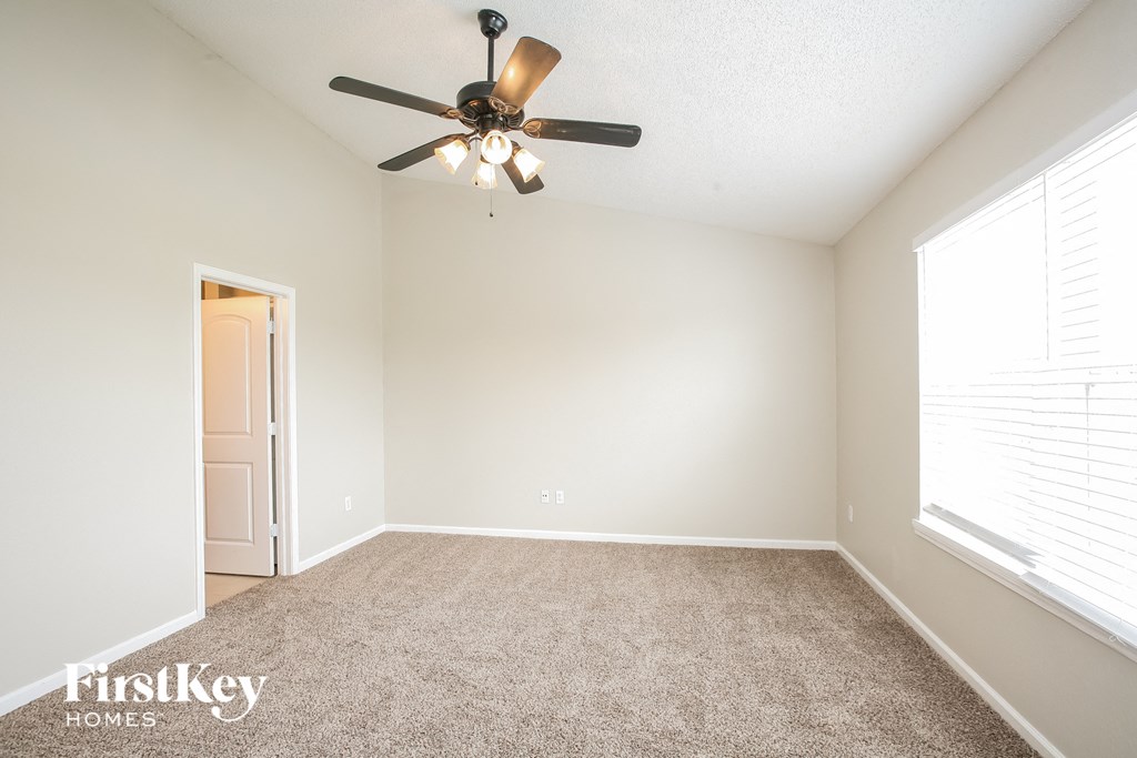 the spacious living room with ceiling fan and carpeting