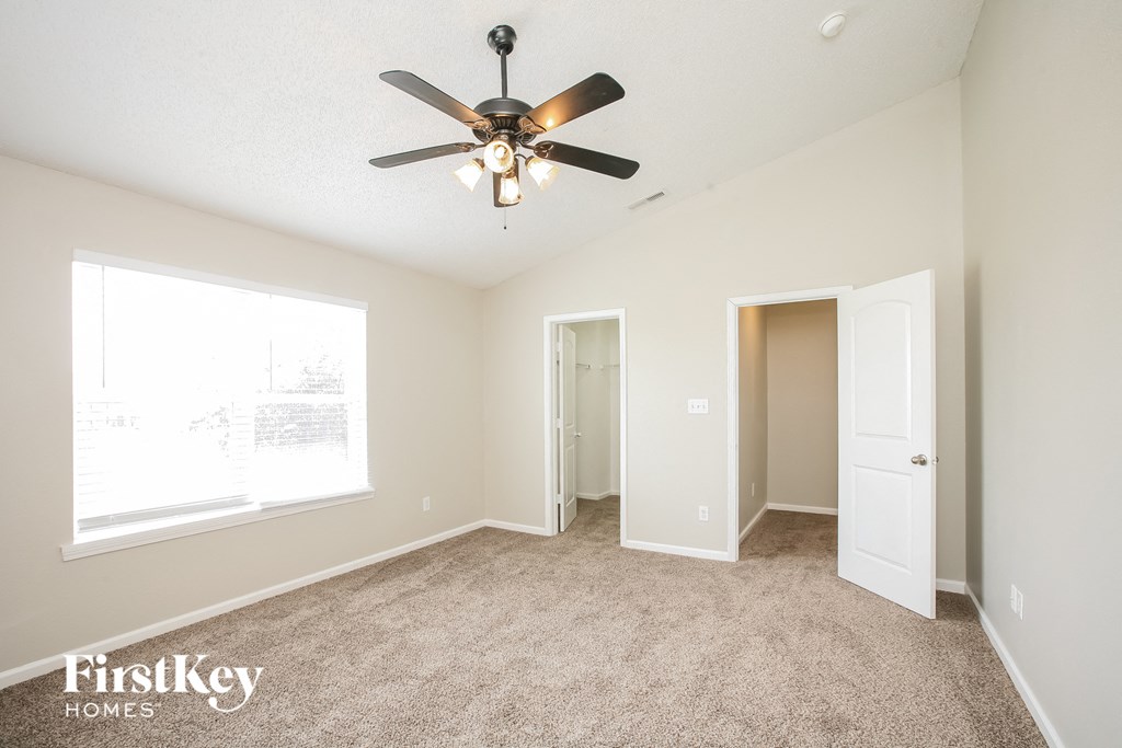 an empty living room with a ceiling fan and a door to a closet