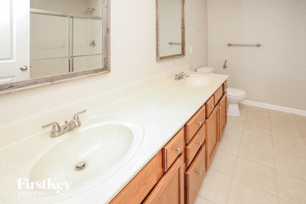 two sinks in a bathroom with a mirror and a toilet