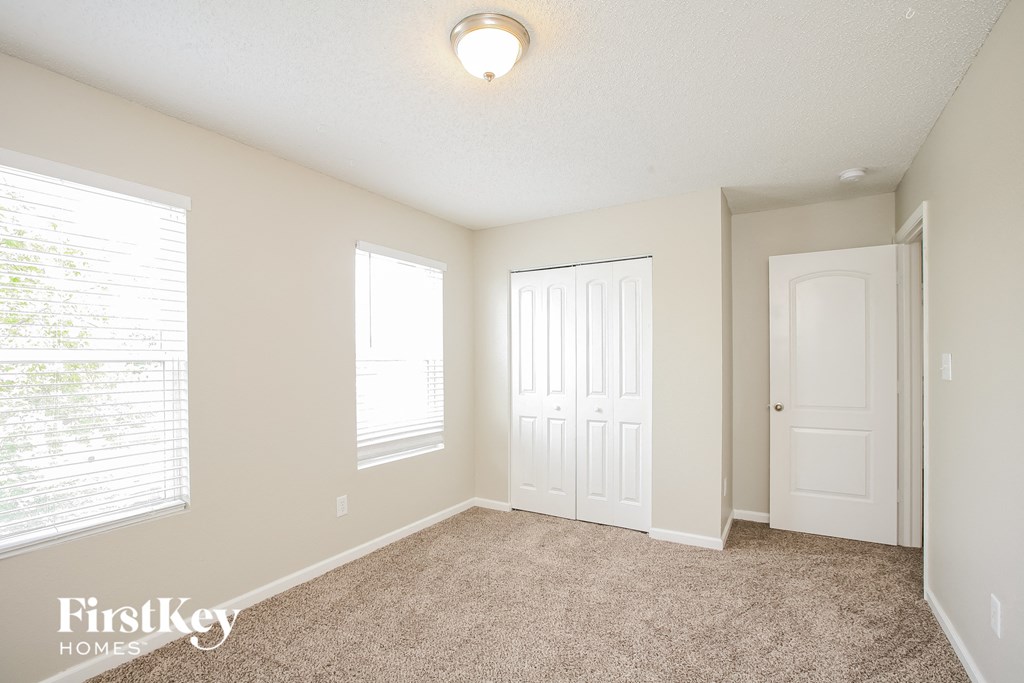 a bedroom with a carpeted floor and a white door and window