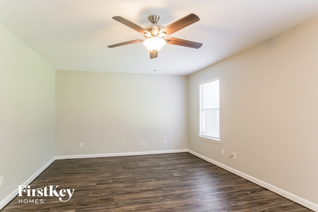 an empty room with a ceiling fan and a window