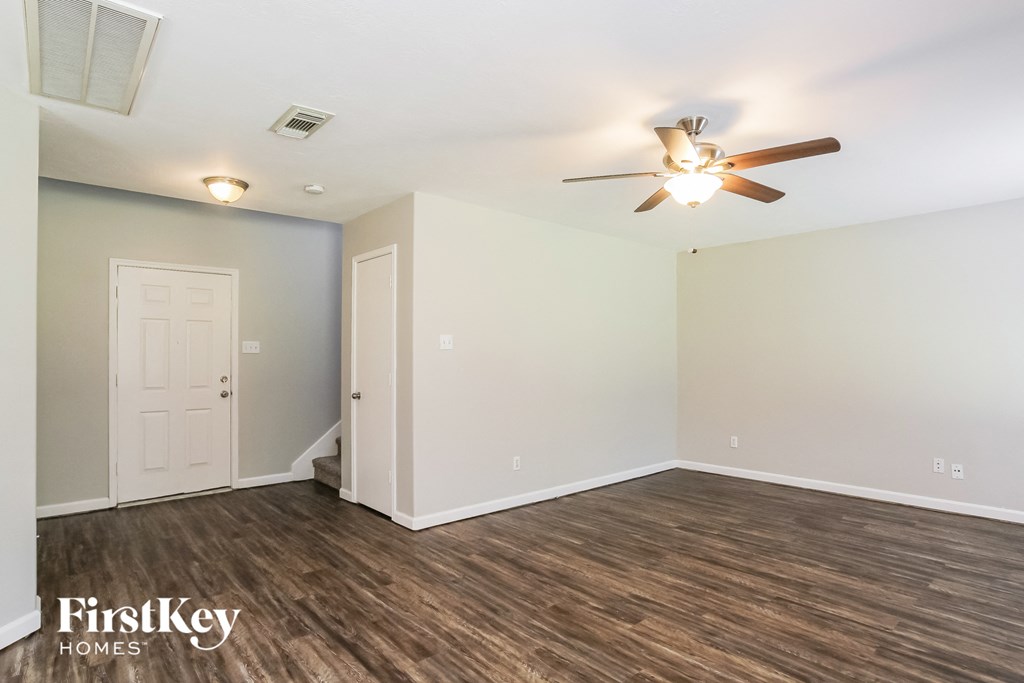 the living room of an empty house with a ceiling fan