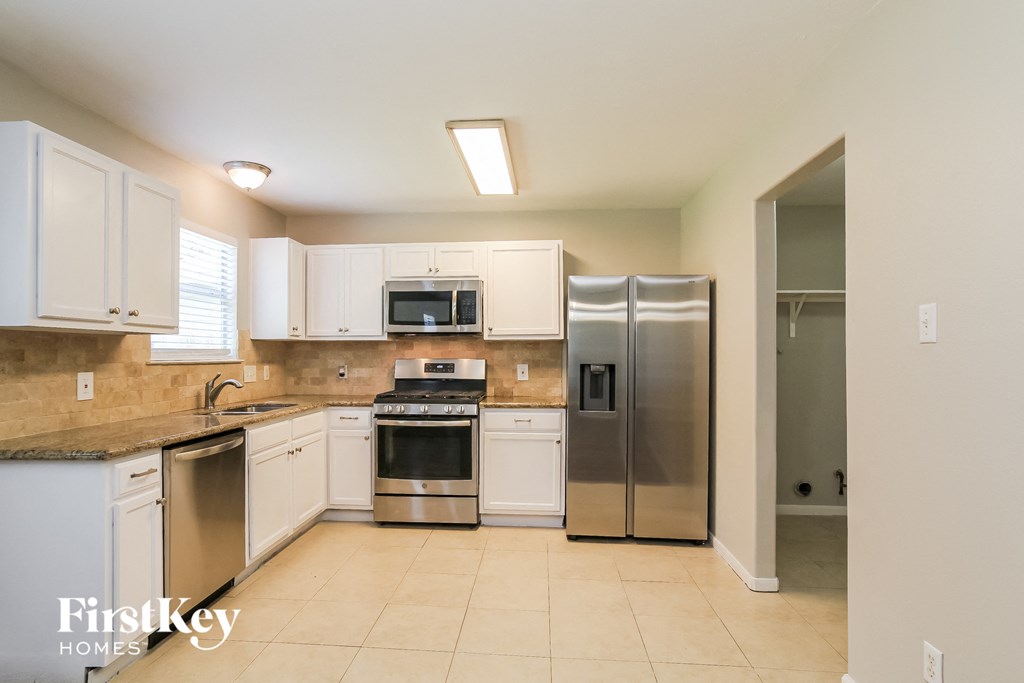 a large kitchen with stainless steel appliances and white cabinets