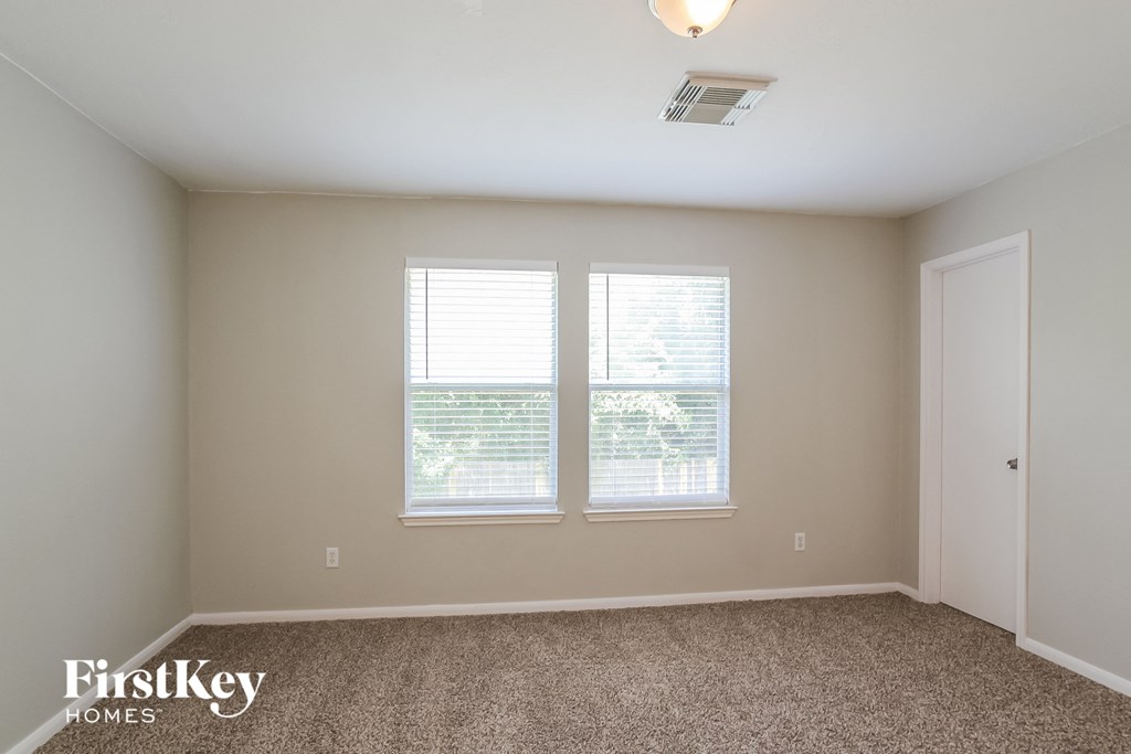 a bedroom with two windows and a carpeted floor