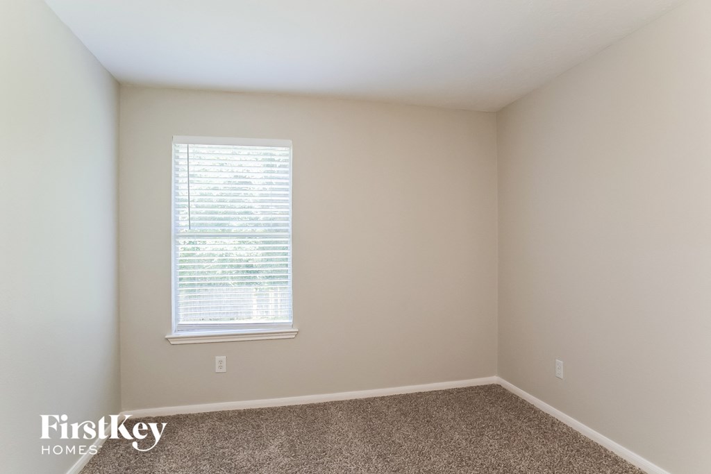 a bedroom with a window and a carpeted floor