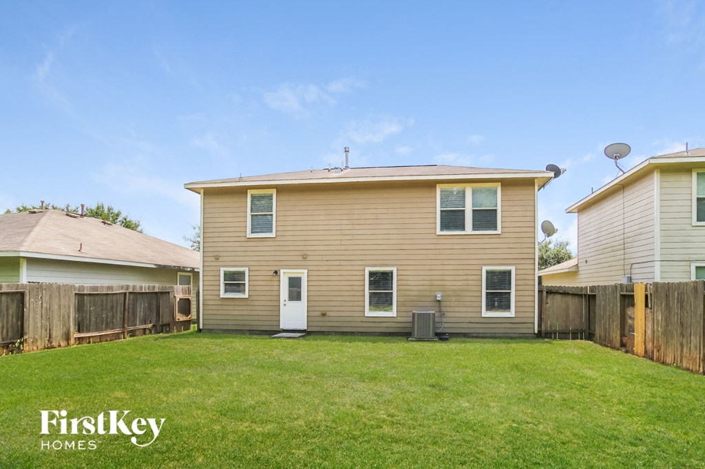 a yellow house with a yard and a wooden fence