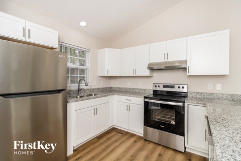 A kitchen with a stainless steel refrigerator and white cabinets.