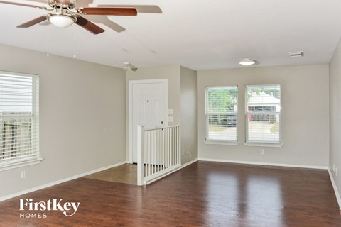 an empty living room with wood floors and a ceiling fan