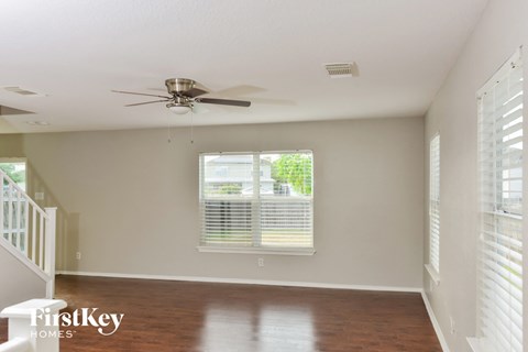 an empty living room with a ceiling fan and a window