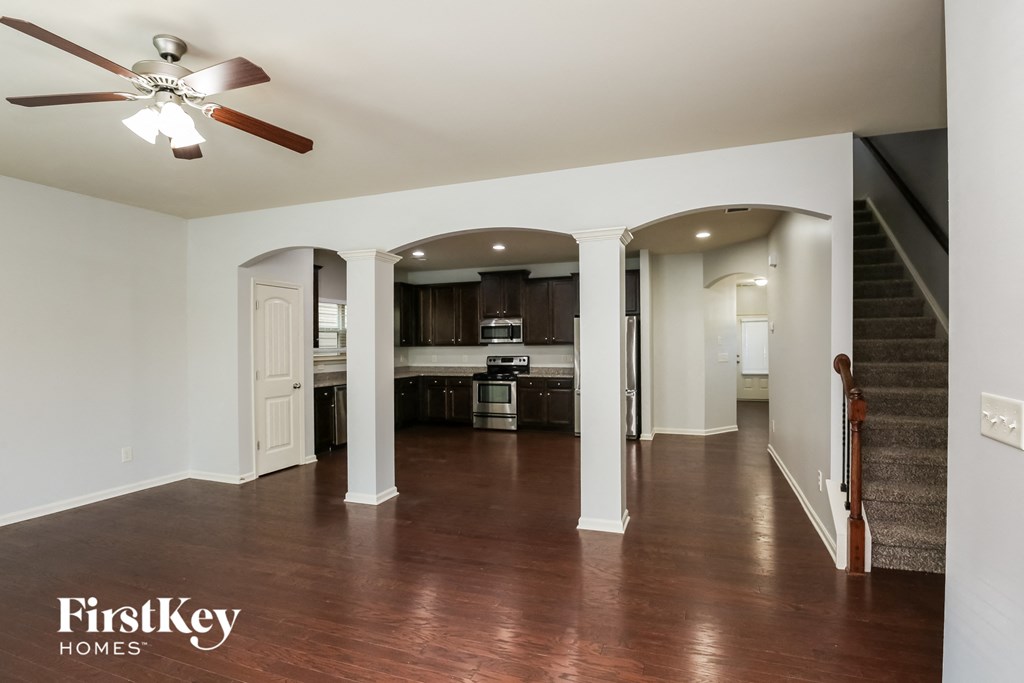 A spacious living room with a wood floor and a ceiling fan.