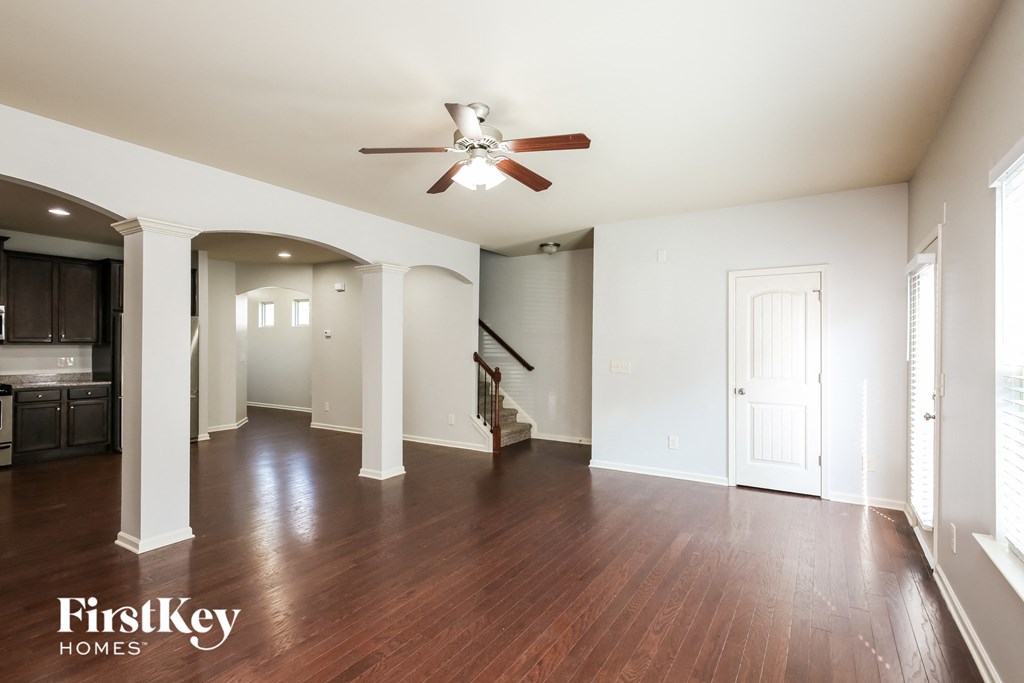 A spacious room with wooden floors and a ceiling fan.