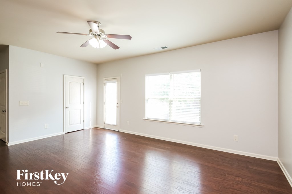 A spacious room with a ceiling fan and wooden flooring.