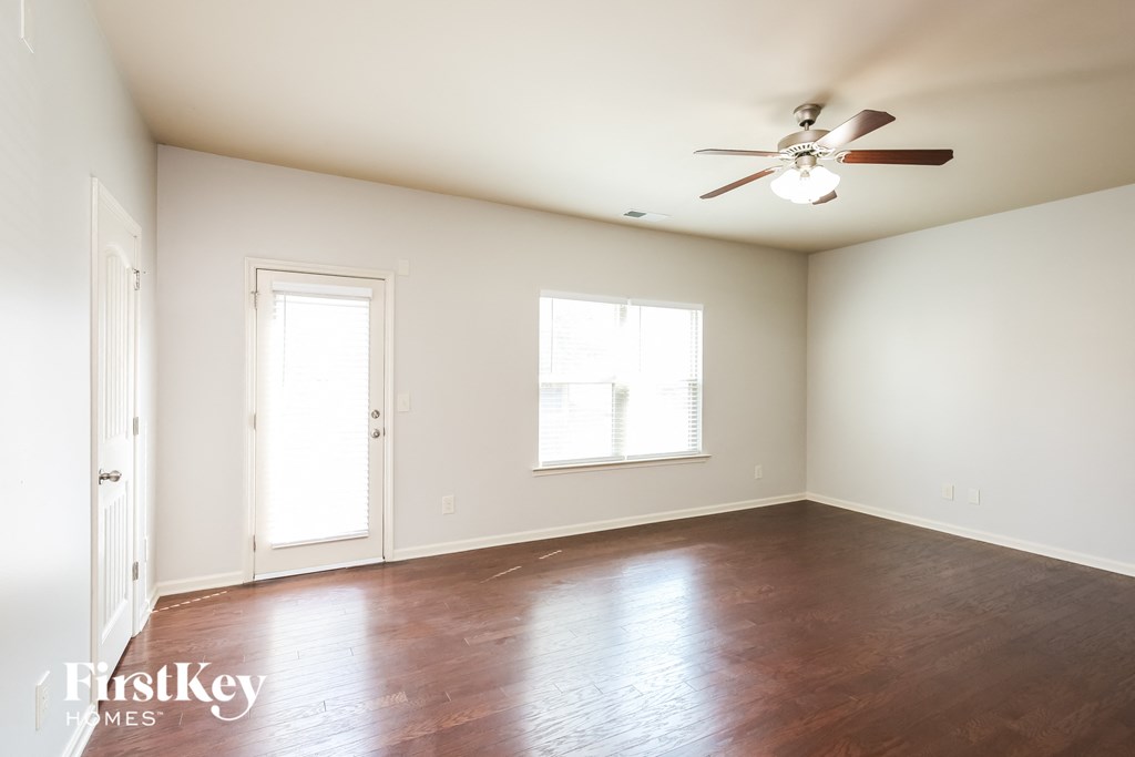 A room with a ceiling fan and wooden floors.