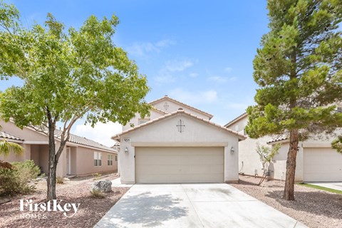 a white house with a garage door and trees