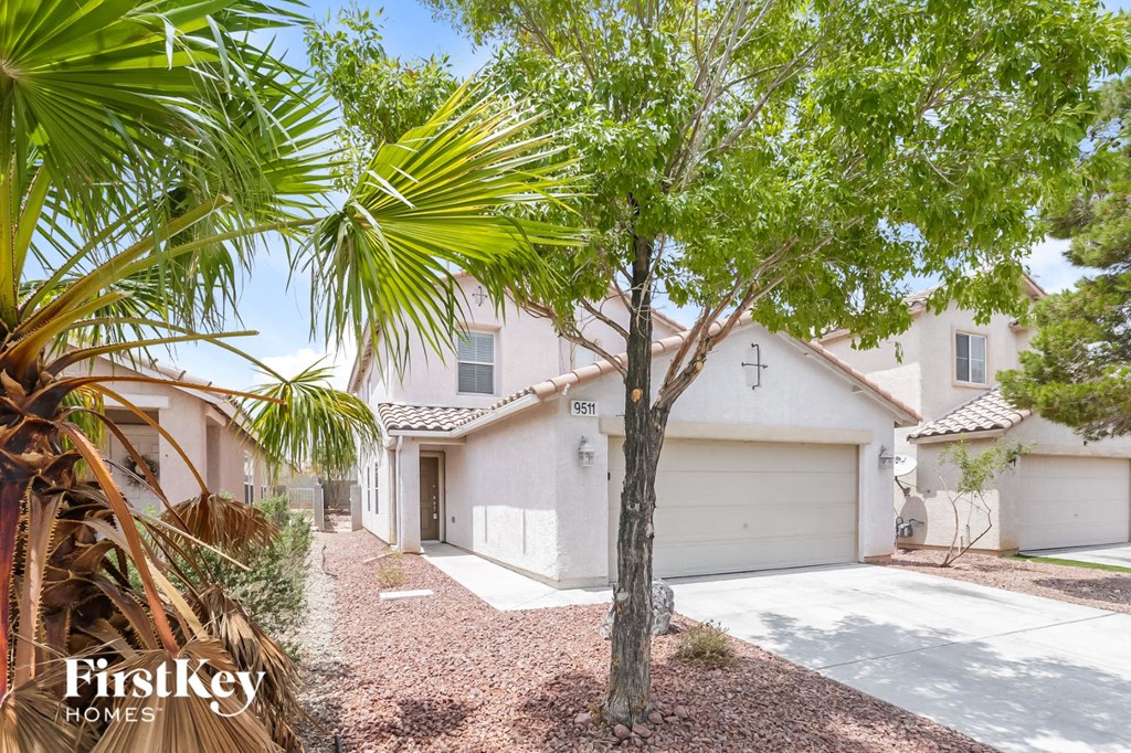a white house with a garage door and a palm tree